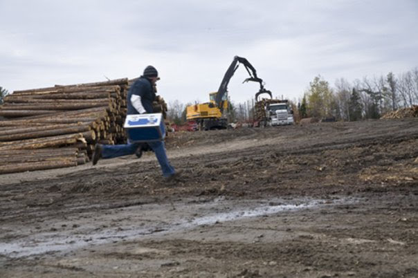 Shawn sprinting through a logging yard carrying camera equipment on American Loggers Season 2, Millinocket, Maine